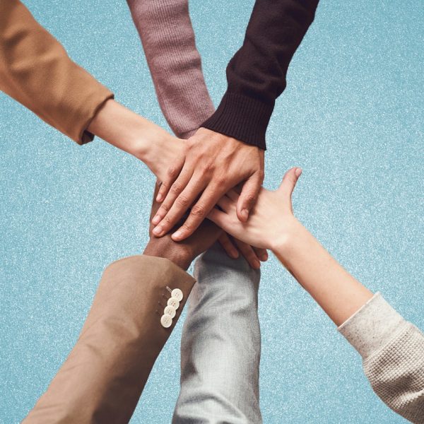Manos unidas de personas diversas como símbolo de solidaridad y colaboración social, representando la importancia del aumento de la asignación tributaria para fines sociales.