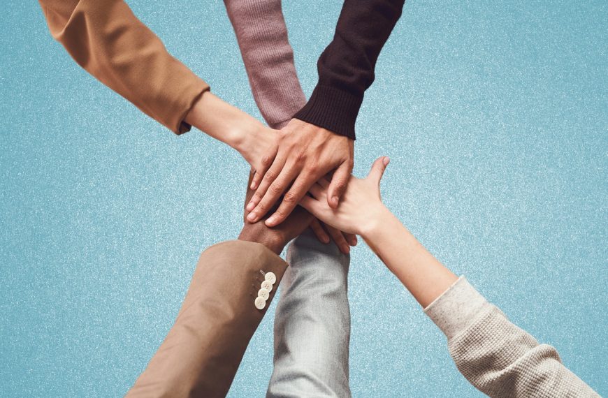 Manos unidas de personas diversas como símbolo de solidaridad y colaboración social, representando la importancia del aumento de la asignación tributaria para fines sociales.