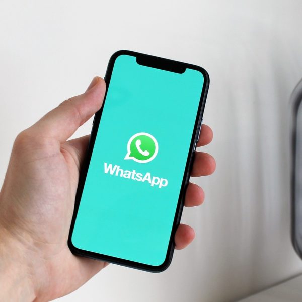 Persona sosteniendo un teléfono móvil con la aplicación WhatsApp abierta en la pantalla.