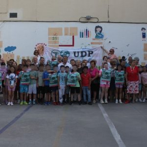Grupo de personas mayores posando sonrientes con niños y niñas durante una actividad al aire libre organizada por UDP el 15 de junio de 2025