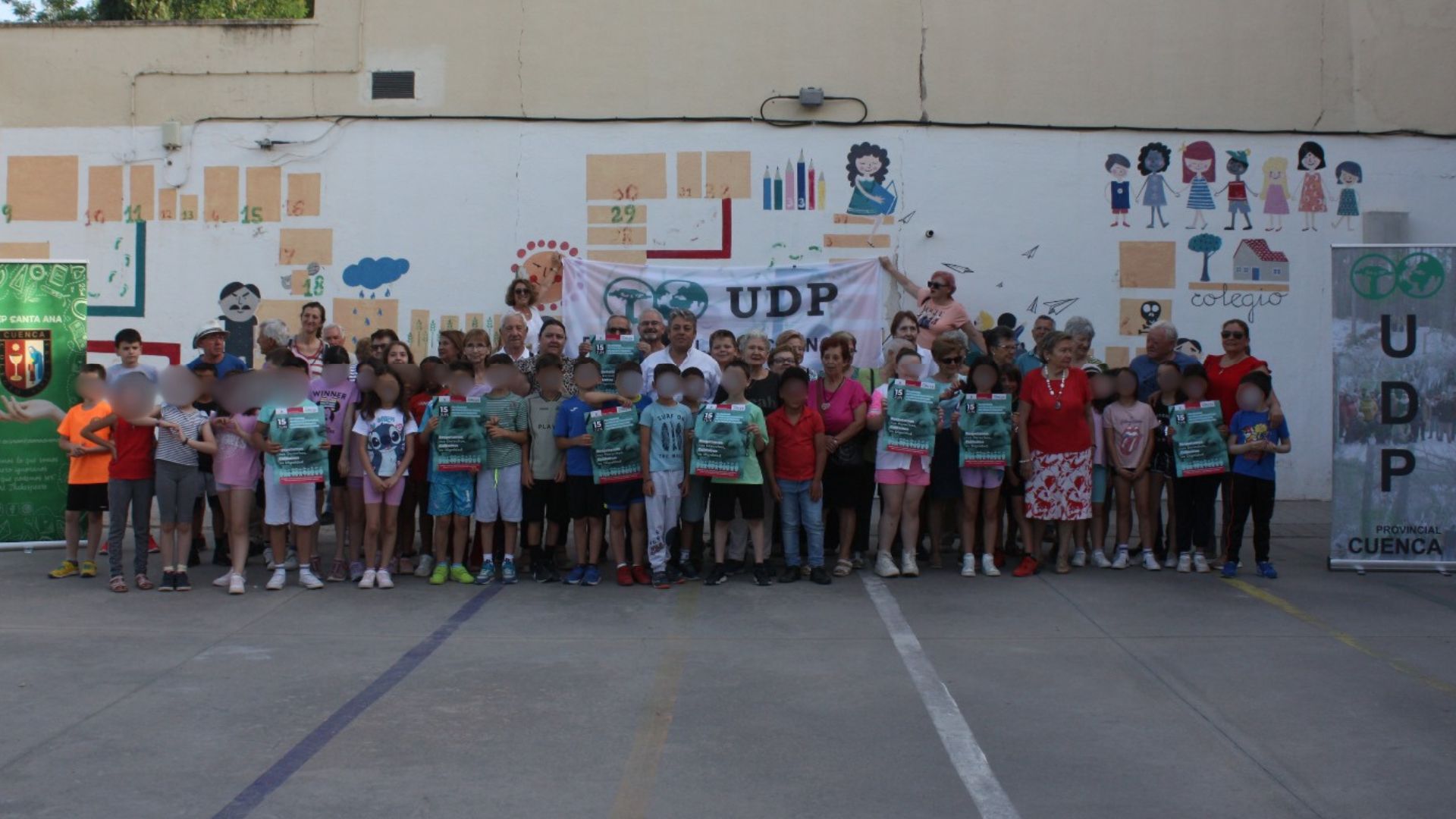Grupo de personas mayores posando sonrientes con niños y niñas durante una actividad al aire libre organizada por UDP el 15 de junio de 2025